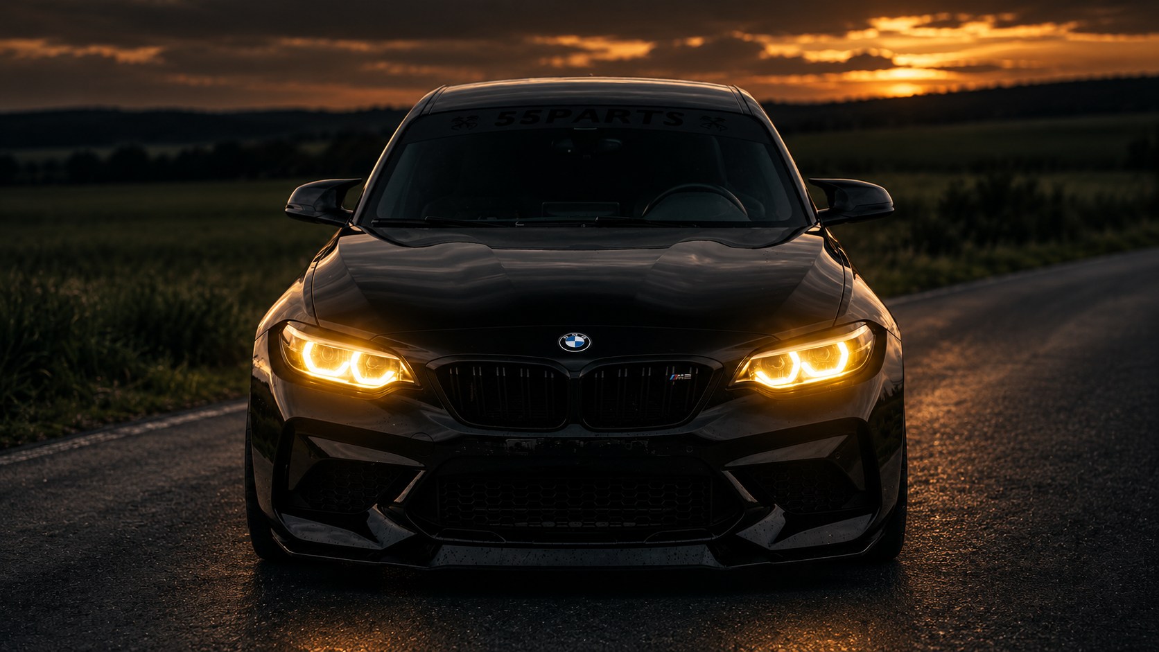 Schwarzer BMW M2 mit gelb leuchtenden Angel Eyes bei Sonnenuntergang